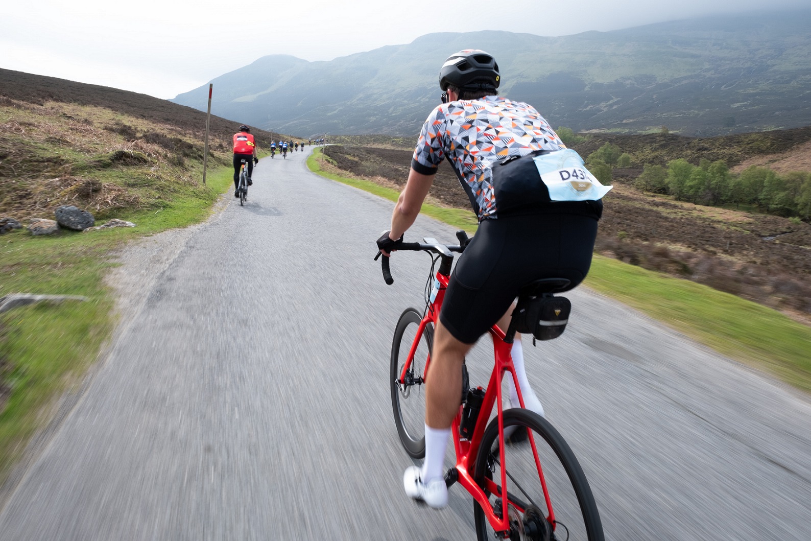 A person riding on a bike on a road as part of an outdoor race