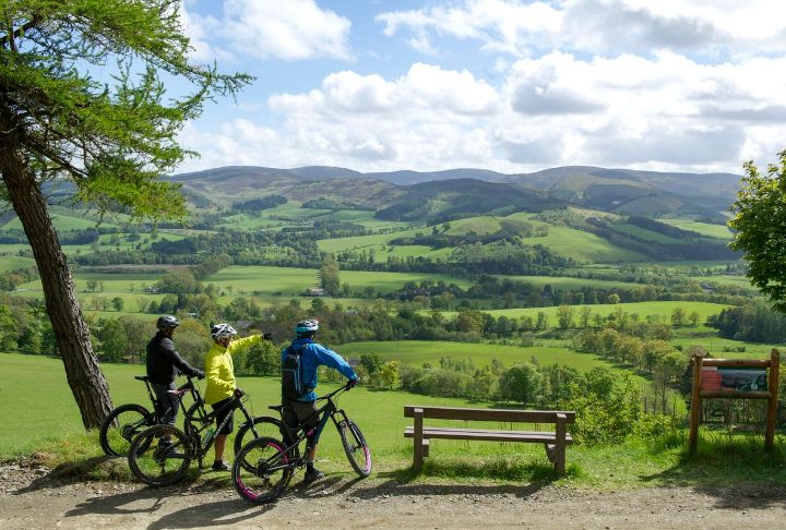 Three cyclists look out over the countryside of the Scottish Borders