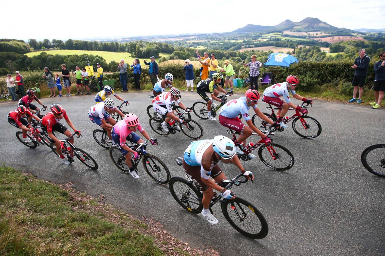 Cyclists on a hill corner being watched by spectators