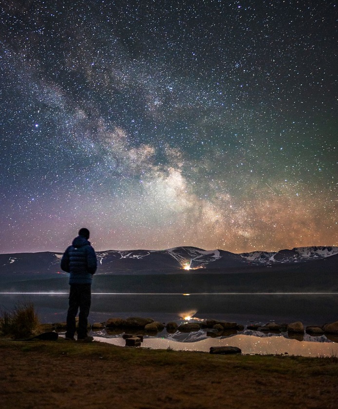 A person looking outwards the dark skies which are lit up with stars