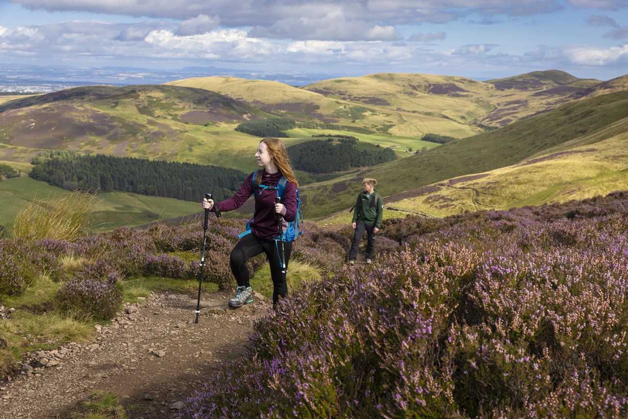 Two people walking in the outdoors / hills during the day