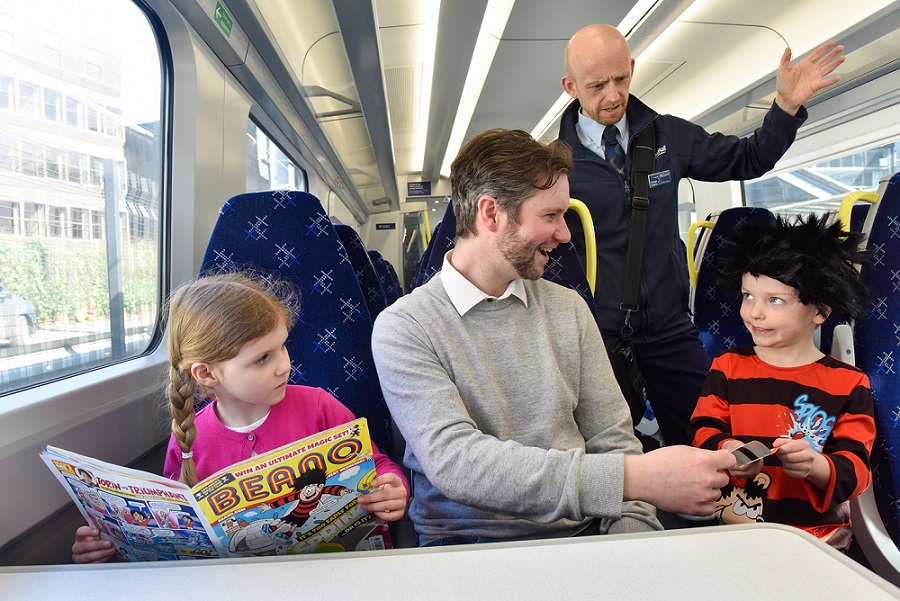 an adult and two children sitting on a train with the train conductor checking tickets,