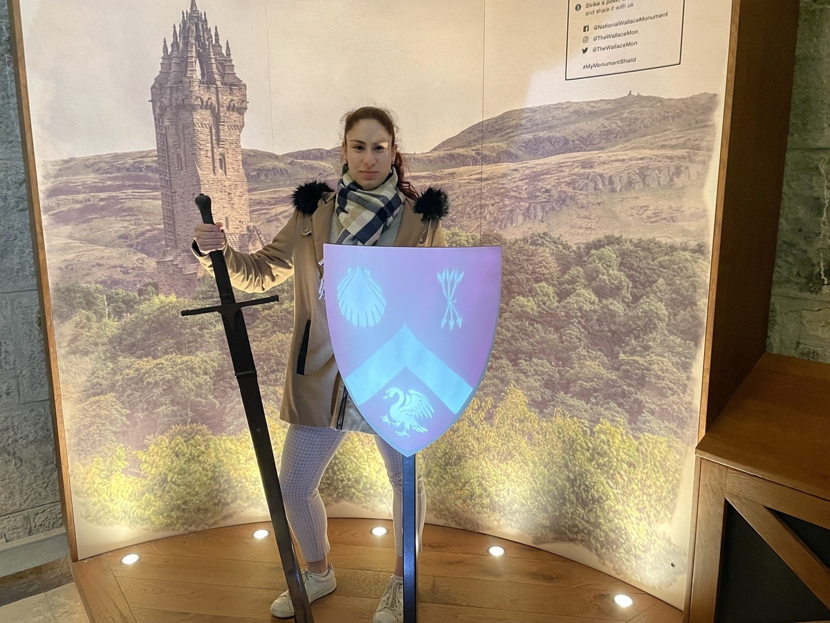 A woman poses with a sword and shield at the Wallace Monument