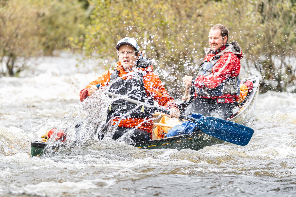 Two men glide over a white water river in a canoe