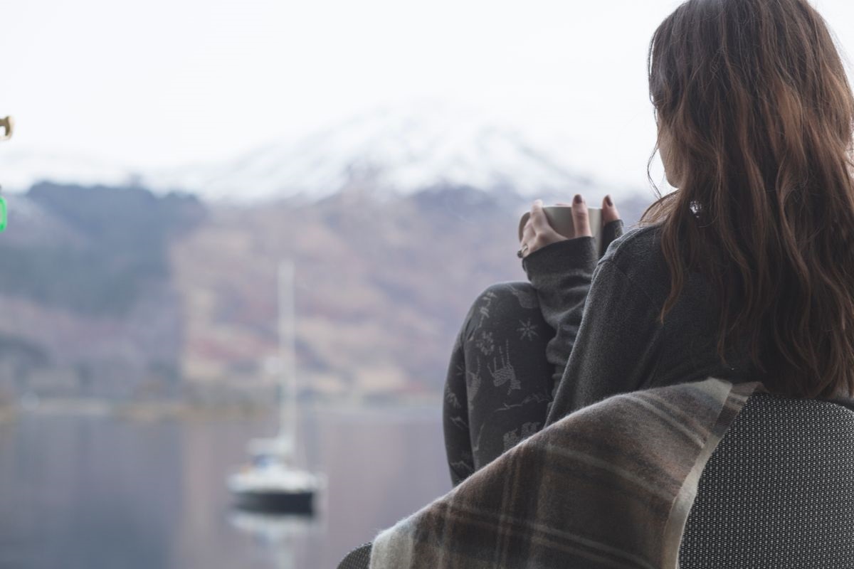 Looking out on a wintery landscape with a warm cup in hand