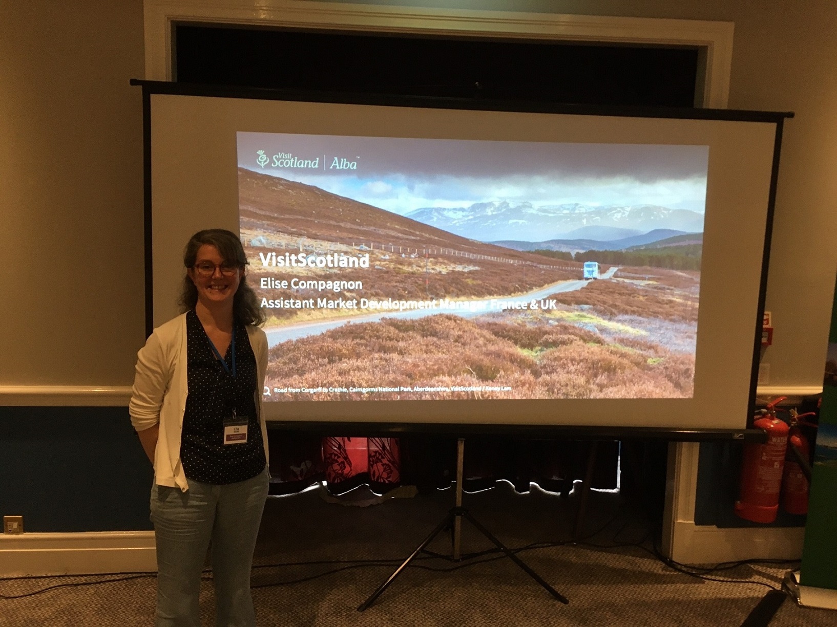 A presenter poses next to their presentation on a white screen