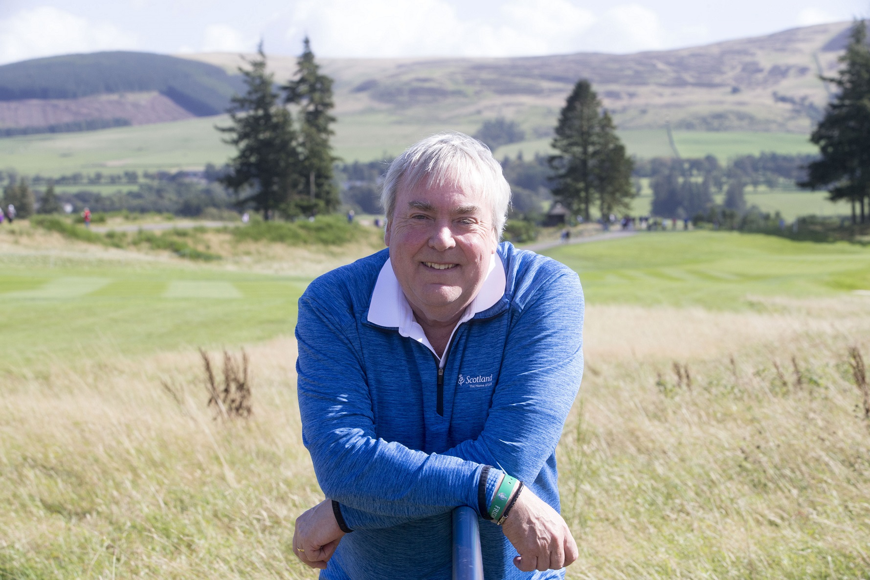 A person pictured outside on the grass smiling to the camera