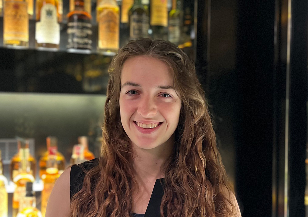 Headshot image of Annika Scneider in front of a cabinet display of Scotch Whisky.