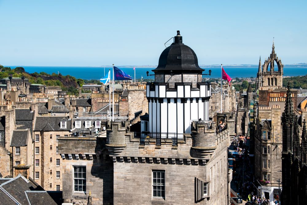 View of the exterior of Camera Obscura tower with from Edinburgh down to the sea behind it.