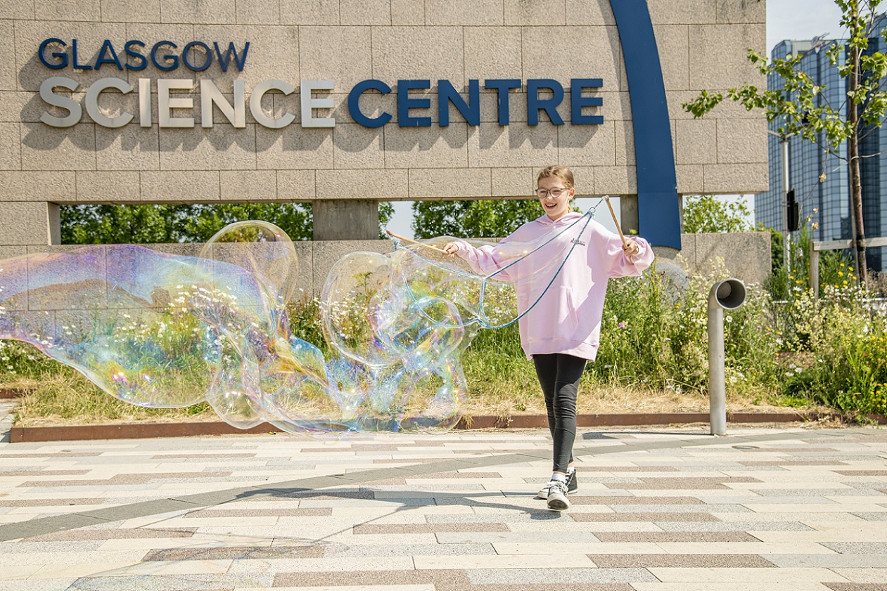 A young girl playing with bubble outside Glasgow Science Centre