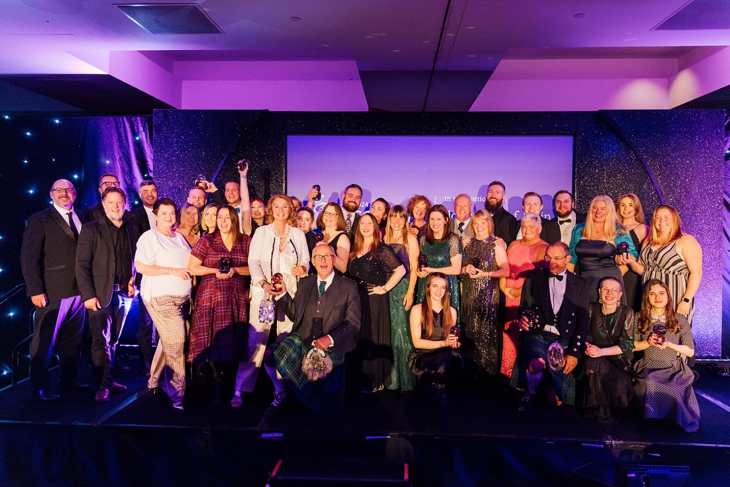 Image of all winners from the evening on stage with their trophies.