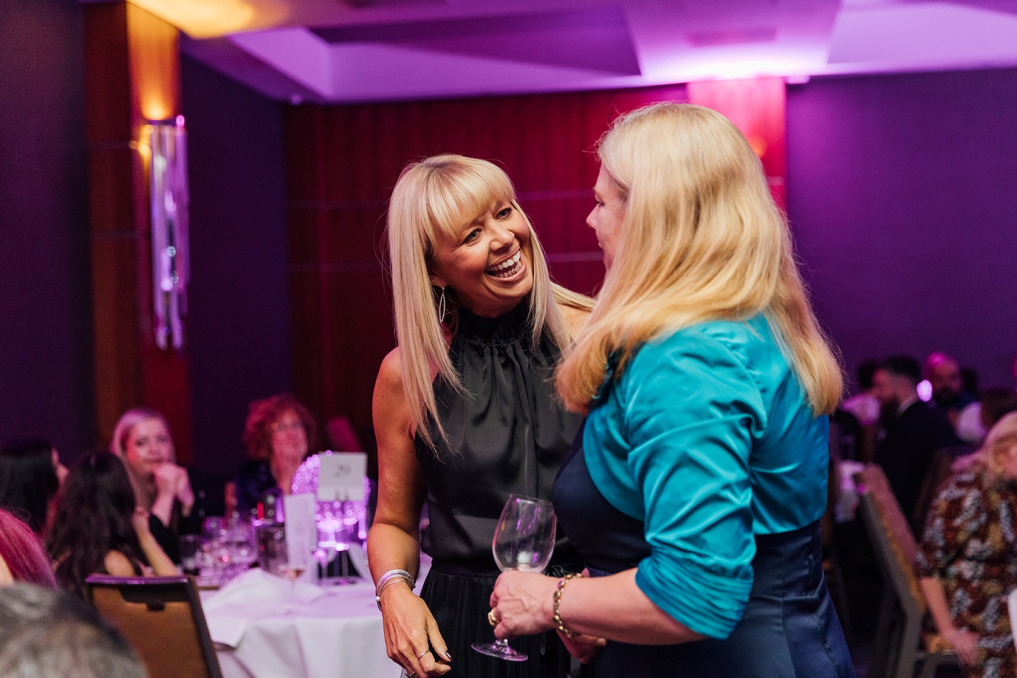 Two people standing in a room talking and smiling together