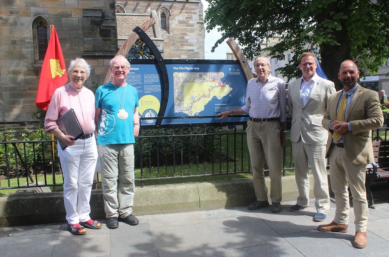 5 people outside standing in front of a display panel