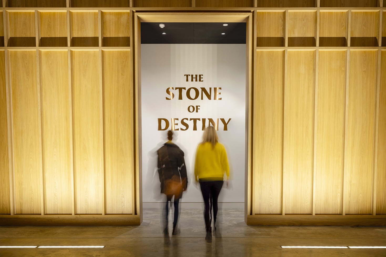 two people walign through doors of amuseumn that reads "The stone of Destiny" the image is slightly blurred